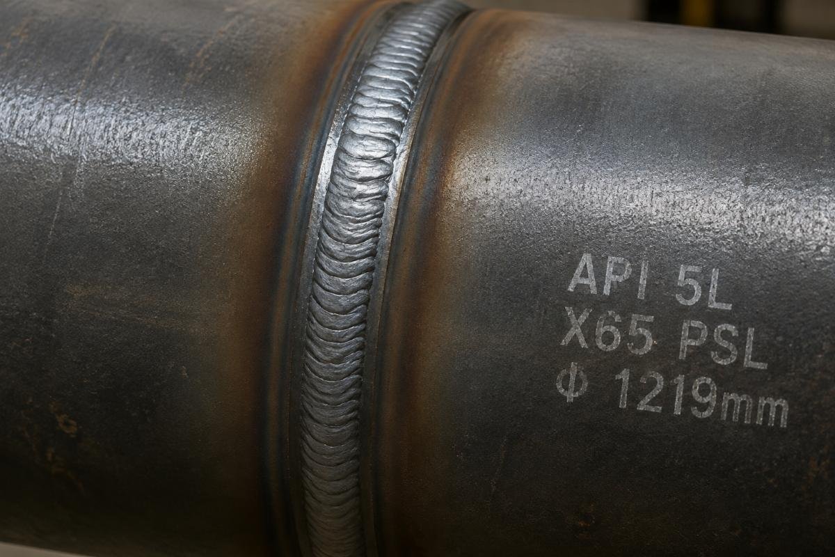 Close-up of a welded joint on an API 5L line pipe showing proper bead profile and no visible cracking